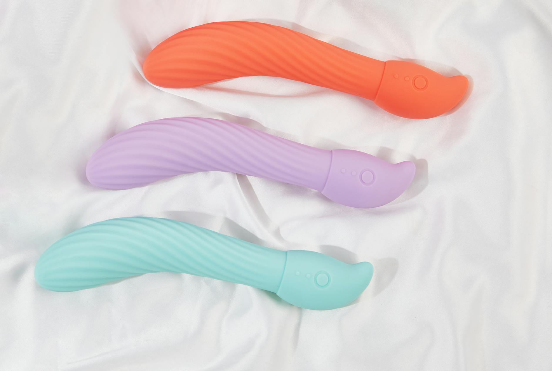 Three colorful lemon vibrators arranged on white fabric, showing their smooth curved design