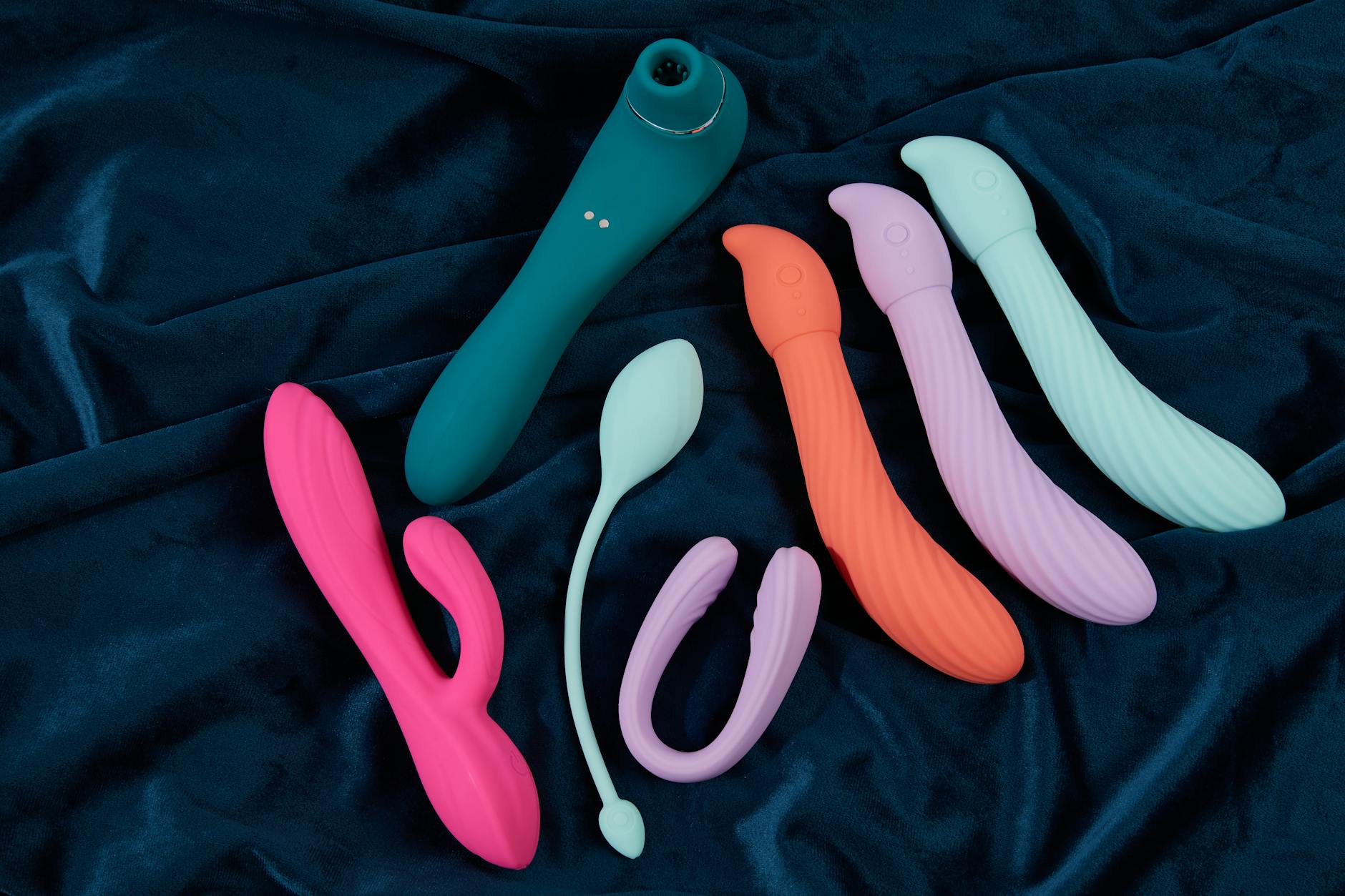Pink vibrator on purple background with heart confetti and candles for a romantic setting