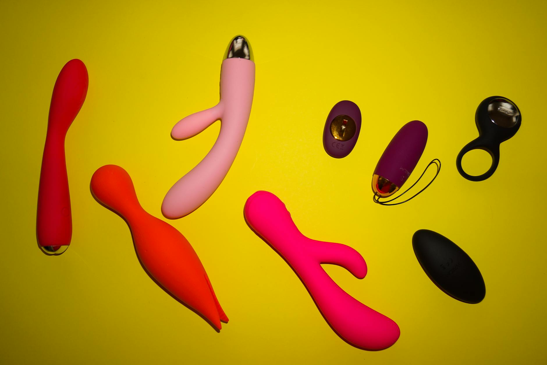 Vibrant array of clitoral vibrators including lemon suction toys displayed on a bright yellow surface