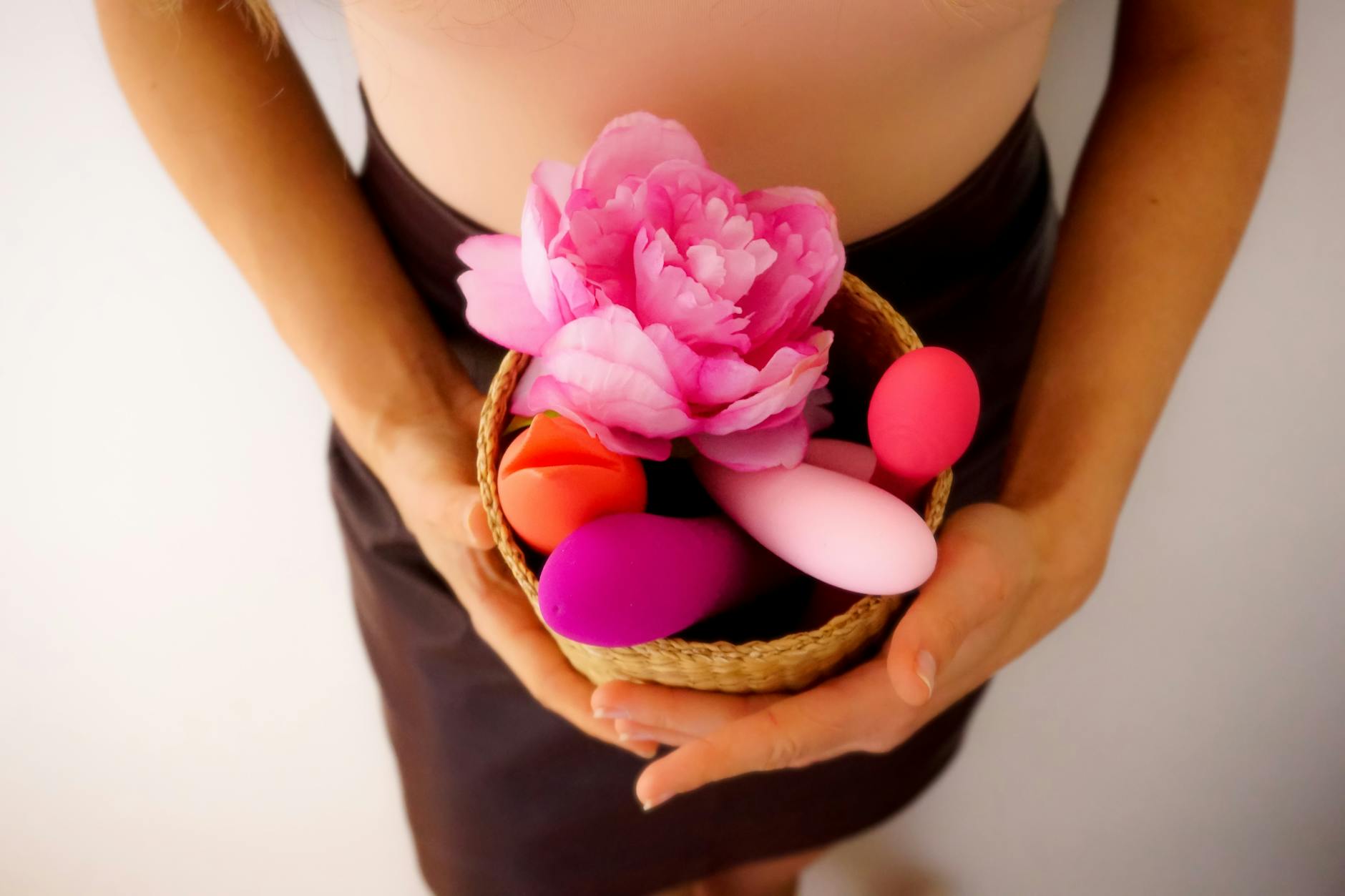 Person holding blue and pink silicone vibrators in a thoughtful pose, representing intimate exploration beyond performance pressure