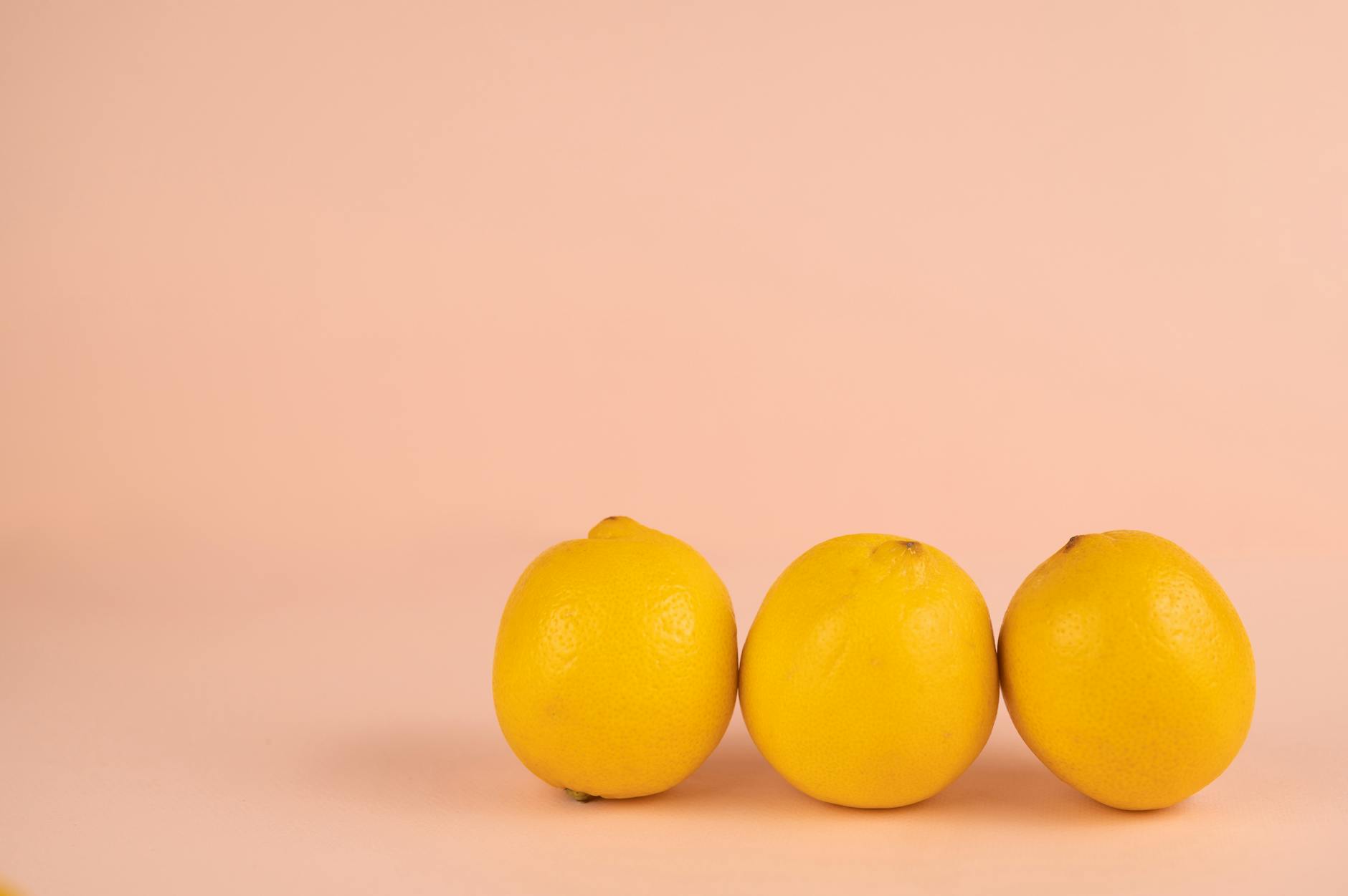 Bright yellow lemons arranged on a pastel green background for fresh, vibrant aesthetic